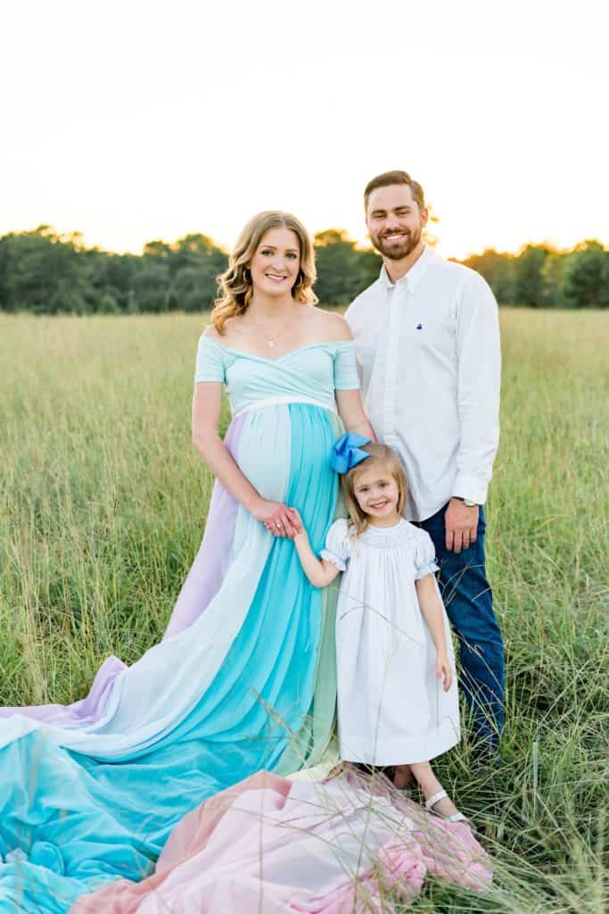 Kendall wearing a rainbow skirt. Her husband and daughter are standing with her.