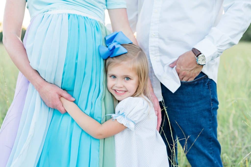 Close up of Kendall's belly and her daughter holding her hand across her belly.