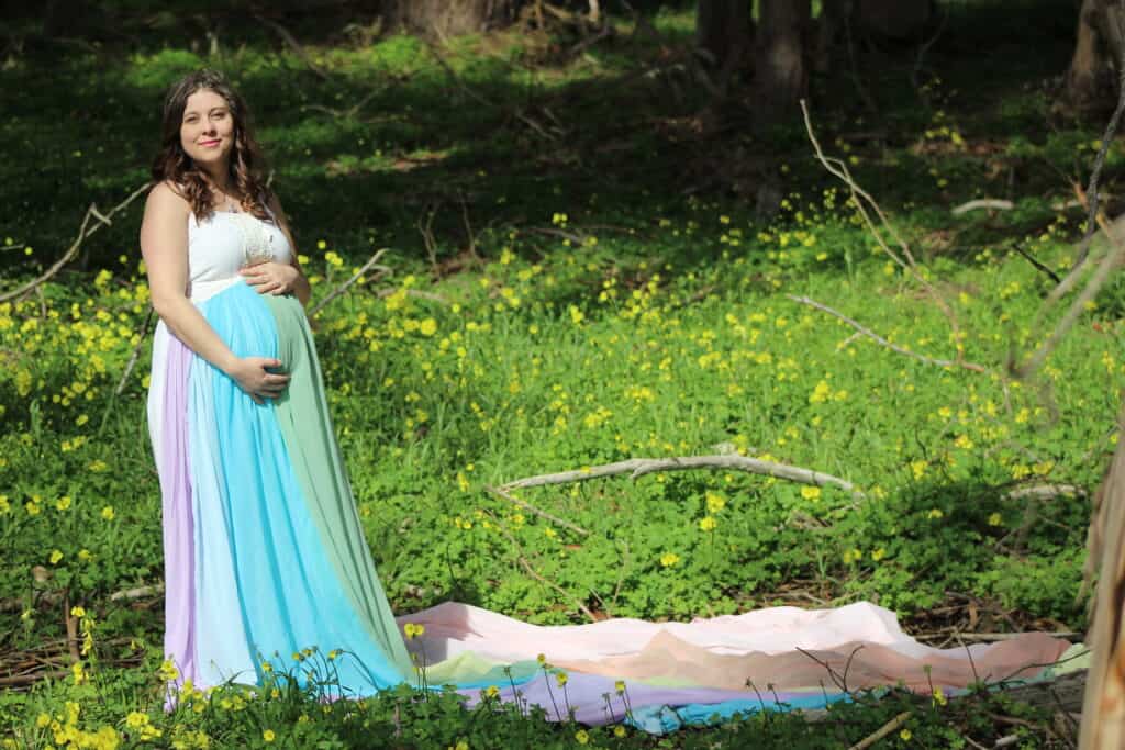 Brittany is wearing the rainbow skirt.  In the background is green foliage with yellow flowers.