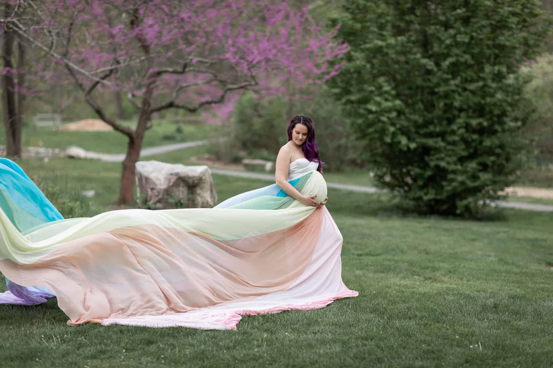 Kristina wears a white dress and the rainbow skirt. The skirt flows out behind her.