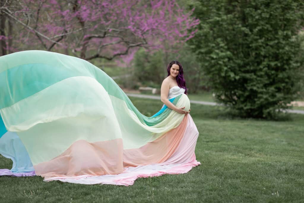 Kristina wears a white dress and the rainbow skirt. The skirt flows out behind her.