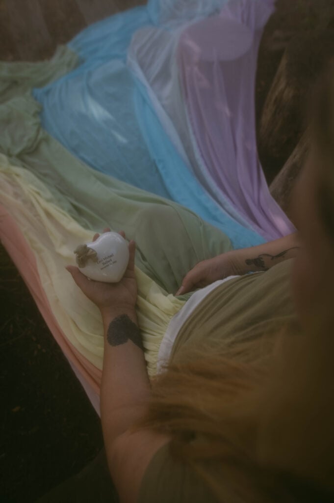 Samantha wears the rainbow skirt. She holds a white heart with her son's name.