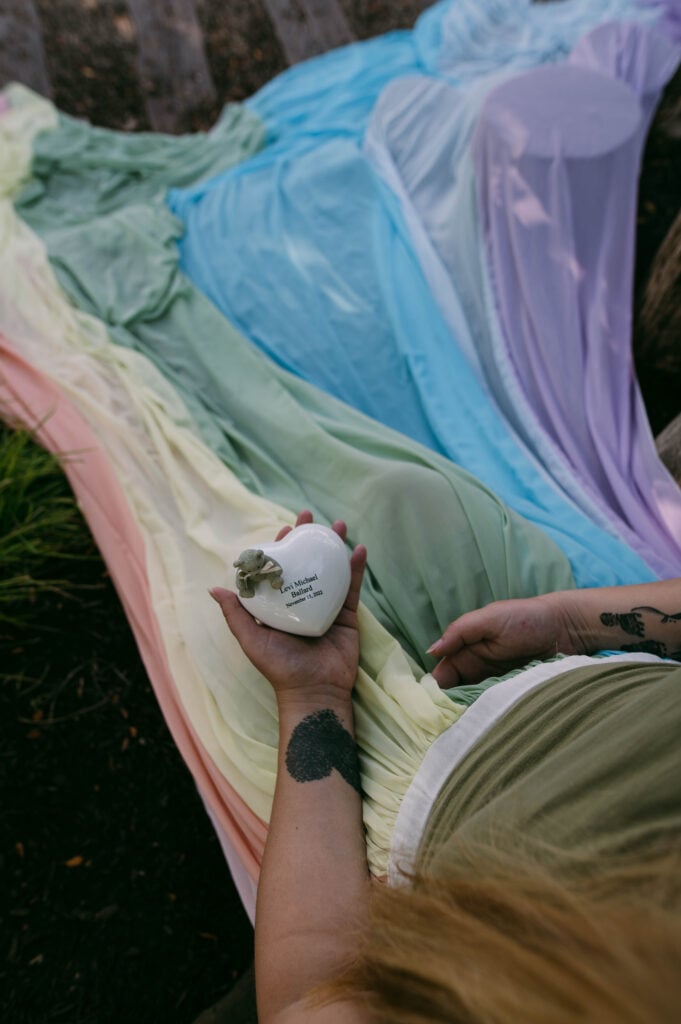 Samantha wears the rainbow skirt. She holds a white heart with her son's name.