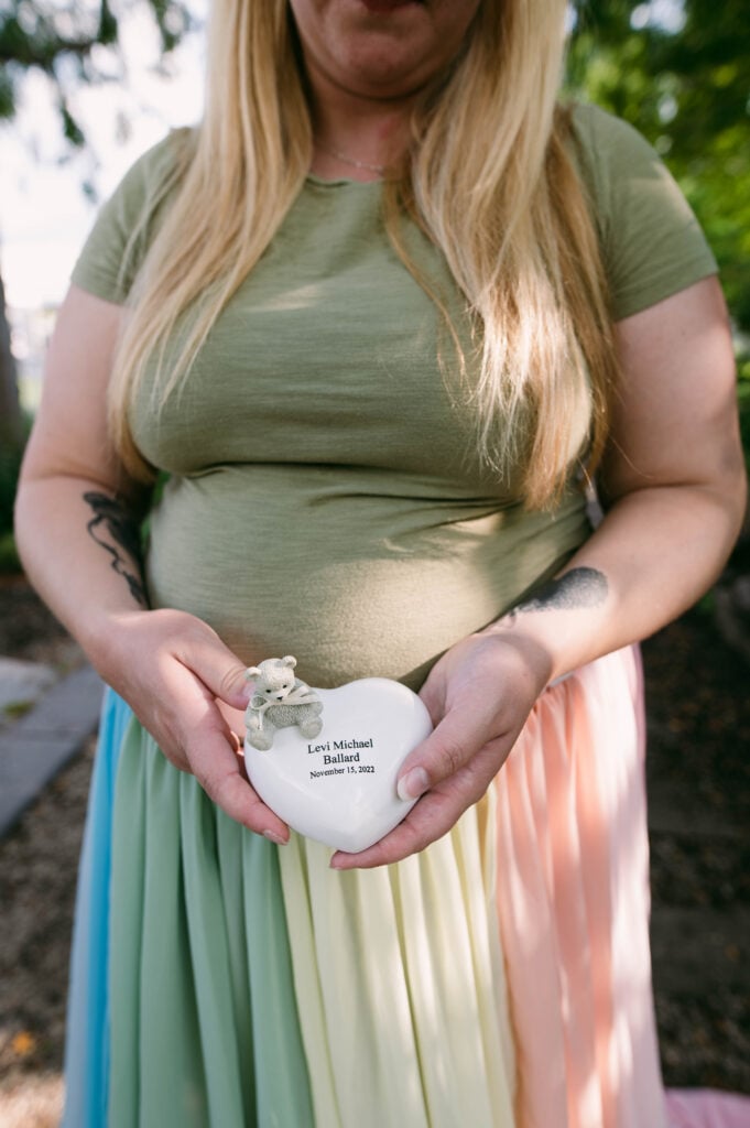 Samantha wears the rainbow skirt. She holds a white heart with her son's name.
