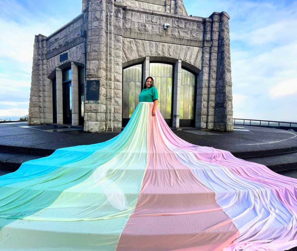 Elisabeth wears a green top and the rainbow skirt. The skirt flows down the steps in front of her.