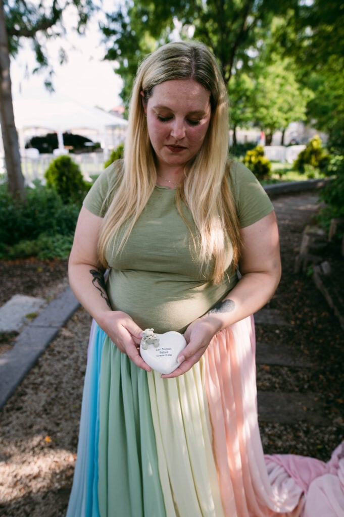 Samantha wears the rainbow skirt. She holds a white heart with her son's name.