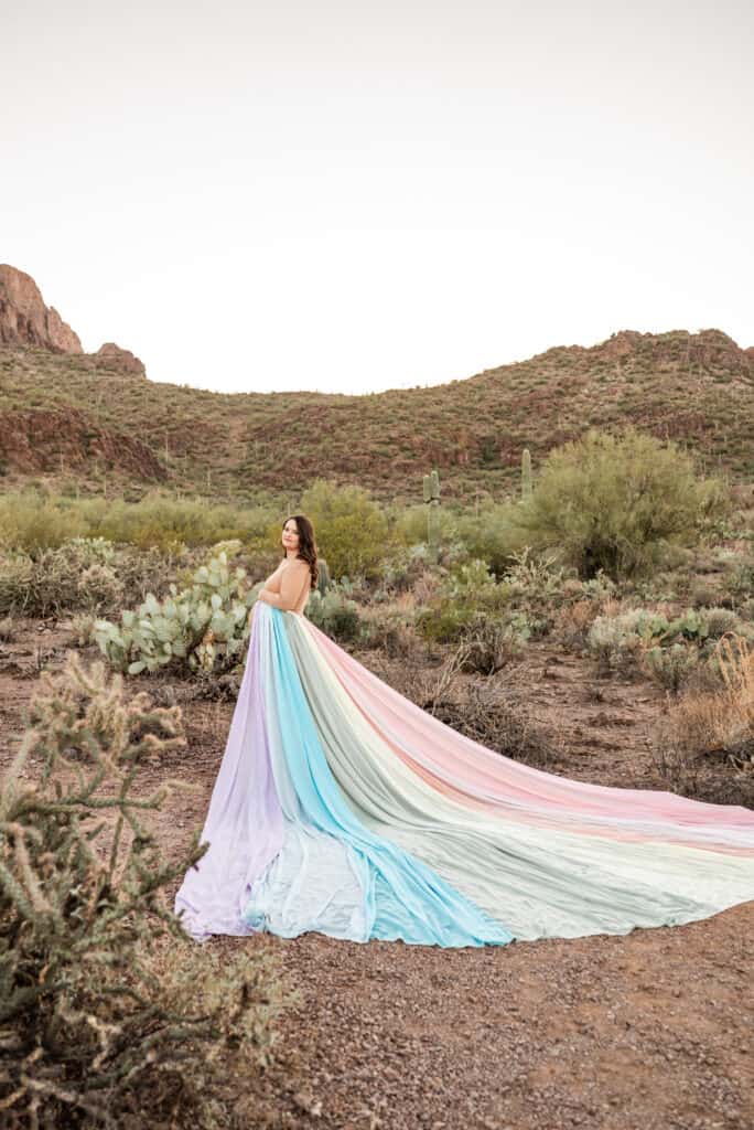 Alex wears the rainbow skirt. There are hills and cacti in the background.