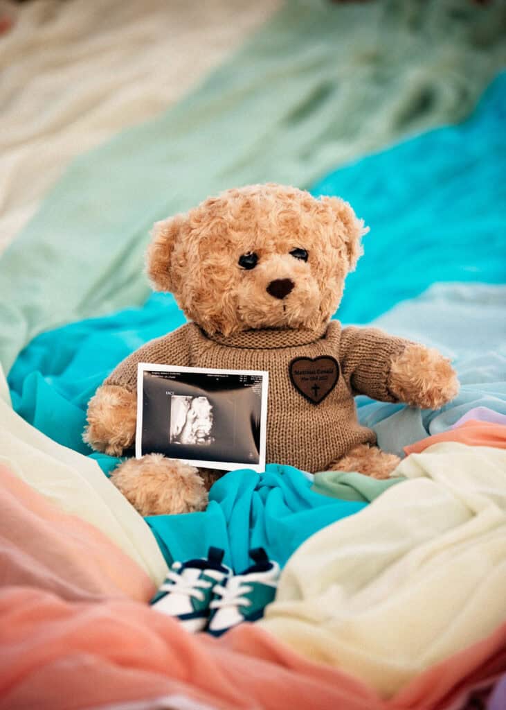 A brown teddy bear and an ultrasound photo sit on top of the rainbow skirt.